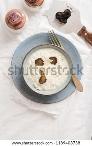 Risotto with black truffle and parmesan cheese in blue plate on white linen tablecloth
