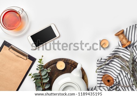 Still life with tea cup and the contents of a workspace composed. Different objects on white table. Flat lay