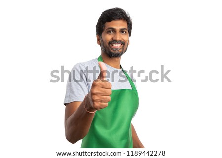 Supermarket or hypermarket male indian staff making thumb up like gesture and smiling as welcoming concept isolated on white studio background