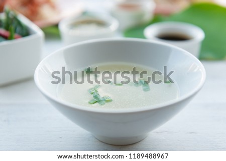 Clear soup in a white cup , served with Hainanese chicken rice