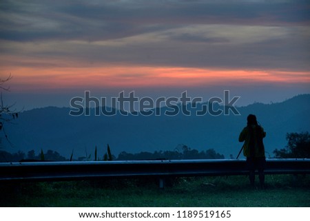 A person is taking a picture with colorful twilight sky in background