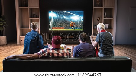 Group of fans are watching a soccer moment on the TV and celebrating a goal, sitting on the couch in the living room. The living room is made in 3D. Royalty-Free Stock Photo #1189544767
