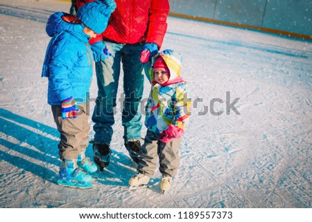 father with two kids- boy and girl- skating in winter