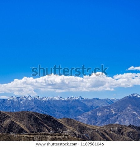 mountains, green forest, meadow, blue sky and white clouds and with a bench for rest in the foreground