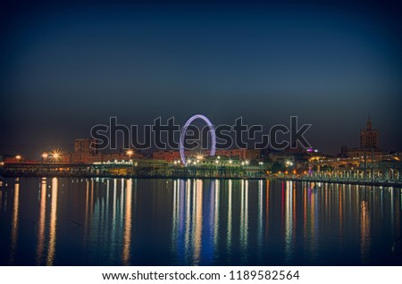 Ferris wheel in Malaga, night view of the city's waterfront with lights reflecting in the water