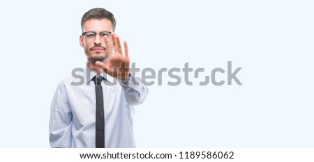 Young business man with open hand doing stop sign with serious and confident expression, defense gesture