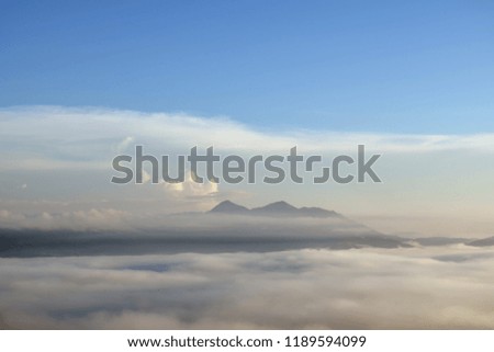 The peak mountain, dense fog cover mountains with background are blue sky, fresh air and mist at dawn