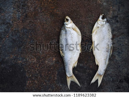 Dried fish lies on a rusty black background