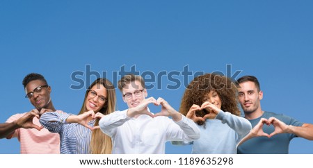 Composition of group of friends over blue blackground smiling in love showing heart symbol and shape with hands. Romantic concept.