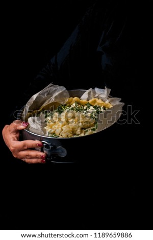 Onion spinach cake. A shape with a cake in his hands on a black background.