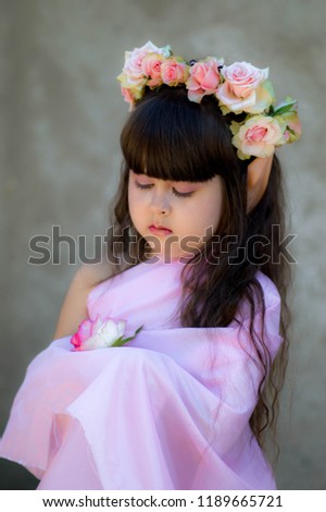 
A little girl in the shape of an elf. Girl in a wreath of roses. The image for a masquerade for Halloween.