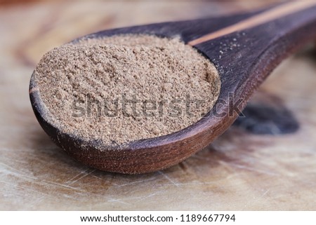 Pumpkin pie spice in a wood spoon over a rustic wooden background. Extreme shallow depth of field with selective focus.
