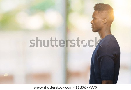 Young african american man over isolated background looking to side, relax profile pose with natural face with confident smile.
