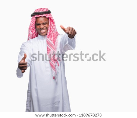 Young arabic african man wearing traditional keffiyeh over isolated background approving doing positive gesture with hand, thumbs up smiling and happy for success. Looking at the camera, winner