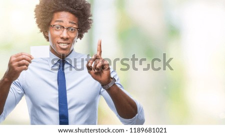 Afro american man holding visit card over isolated background surprised with an idea or question pointing finger with happy face, number one