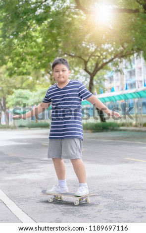 Obese boy learn to ride skate board in fitness park, Active outdoor sport for kids.
