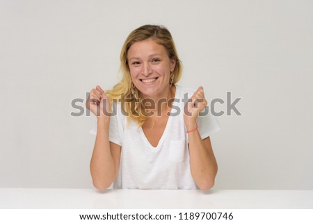 Portrait of a beautiful girl on a white background at the table. She sits right in front of the camera in different poses, smiling and showing different emotions.