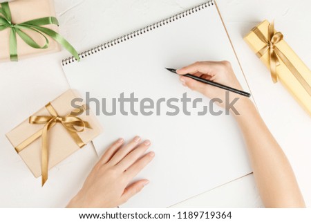 Gifts on blank notebook sheet on a white background, top view. Flat lay with copy space. Congratulatory letter with presents on the table.