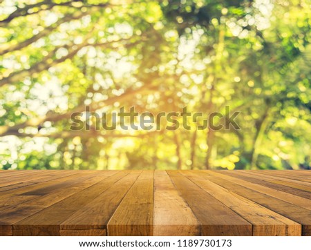 wood table and Abstract blur image of green tree bokeh with sun and sunlight for background usage.