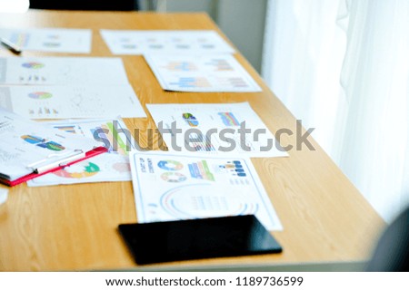 Wooden desk in sunny office with large windows Have a document placed next to it. With black phone The desk of the businessman.