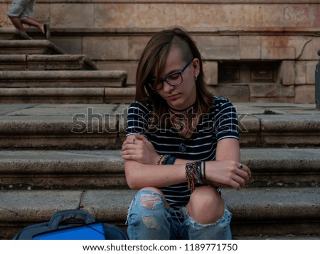 A teenage woman gesturing on the stairs of an old building on a university campus