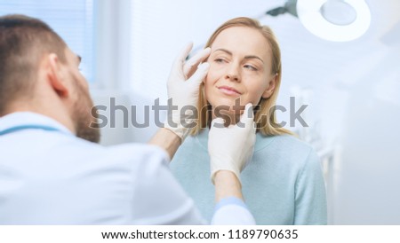 Plastic / Cosmetic Surgeon Examines Beautiful Woman's Face, Touches it with Gloved Hands, Inspecting Healed Face after Plastic Surgery with Amazing Results. Royalty-Free Stock Photo #1189790635