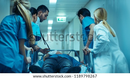 Emergency Department: Doctors, Nurses and Surgeons Move Seriously Injured Patient Lying on a Stretcher Through Hospital Corridors. Medical Staff in a Hurry Move Patient into Operating Theater. Royalty-Free Stock Photo #1189798267