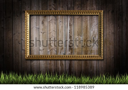 Golden frame and green grass over a wooden background
