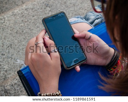A teenage woman with a smart phone on her hands on the stairs of an historial building Royalty-Free Stock Photo #1189861591