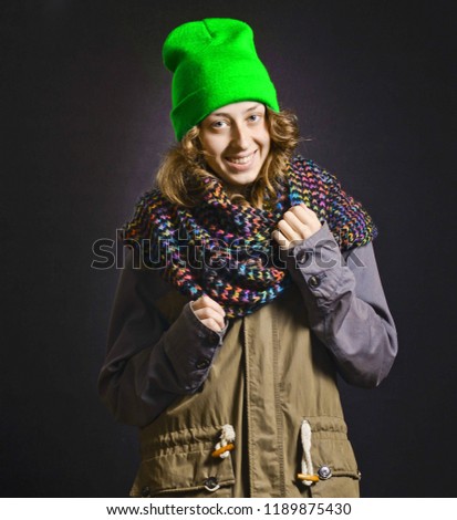 Young happy woman in a coat park, scarf, hat in studio on a black background. Hipster fashion. Autumn winter clothes
