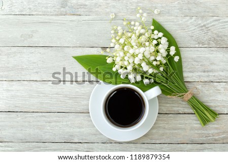 Still life with a cup of coffee and flowers on a wooden table....