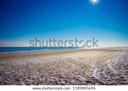 white snow on sand beach meet clam tropical ocean with small waves and blue sky in sunny day on Winter - Ocean City, Maryland USA  Royalty-Free Stock Photo #1189885696