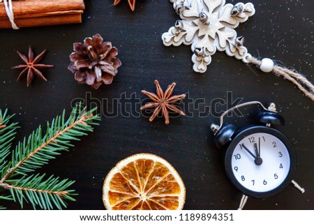 Christmas New Year Composition winter objects clock, fir branch, baubles, cinnamon, ball on dark black background. Flat lay, top view, copy space. Christmas december time for celebration concept