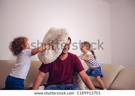 Happy childhood - children boy and girl playing with smiling father together at home
