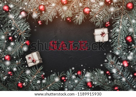 Christmas greeting card in black background. Frame of fir branches decorated with red balls. Decorative gifts. Sale text. Snow effect. Royalty-Free Stock Photo #1189915930