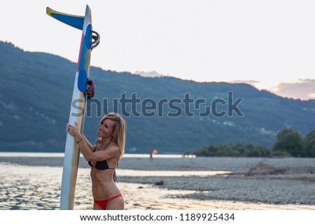 Portrait of beautiful young Caucasian girl standing at beach with her surf board.
