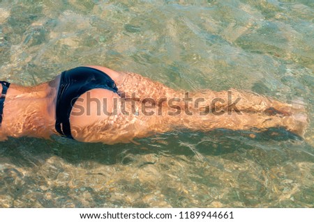 Young woman in bikini lying in the water in the beach. 