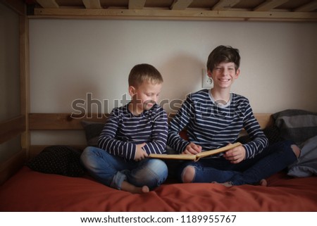 The brothers read together on two bunk beds in the nursery, the concept of kinship and childhood, a real interior, a dark style
