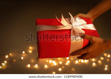 Hand hold red gift white to give somebody,bokeh light background.For special day,happy new year,christmas.
