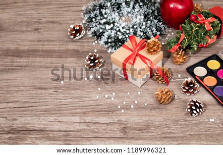 Top view Christmas celebration or Autumn decorations with present or gifts box, color plate,pine cone, apple, Tree and snowflake on wooden background with copy space/ Christmas and autumn concept