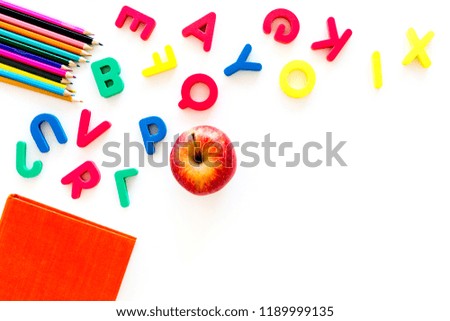 Primary school concept. Letters of english alphabet, book, apple and color pencils on white background top view copy space