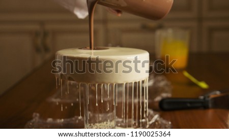 Cheesy mousse cake. Confectioner girl pours a delicate biscuit glaze. Master class in a home sweet shop. Glaze spreads on the cakes. Adding chocolate glaze to create a picture.
