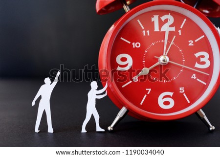 miniature paper people with  a large clock, an alarm clock on a black background. The concept of time and man