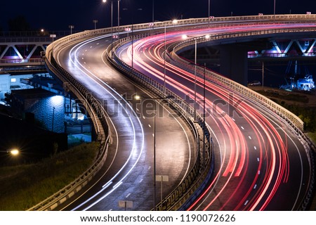 Interchange bridge road with car light streaks. Night light painting stripes. Long exposure photography.