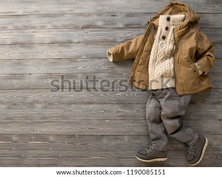 Childrens clothing, shoes (knit sweater, hooded canvas jacket, jeans, suede boots). Outfit for little boy. Winter, autumn collection. Fashion, shopping concept. Template for online store. Flat lay