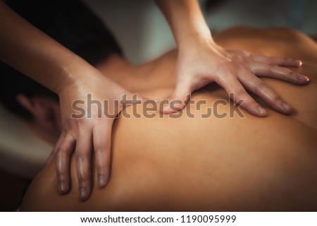 Physiotherapist massaging male patient with injured shoulder blade muscle. Sports injury treatment. Royalty-Free Stock Photo #1190095999