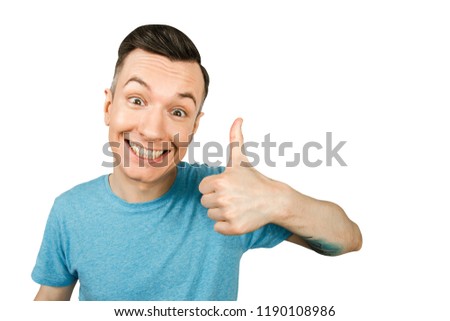 Young smiling guy, dressed in a blue t-shirt, show thumbs up on a isolated white background.