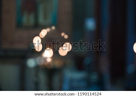 Bokeh from the burning candles in orthodox church. Icons and faces of Saints on a background. Dark background, motion blur
