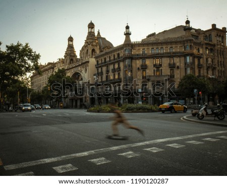 Wide crossroad with skateboarder in long exposure and vehicles on background with green trees and building with classical architecture