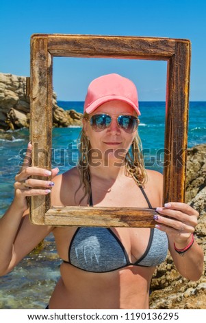 Pretty woman on beach with wooden picture frame 